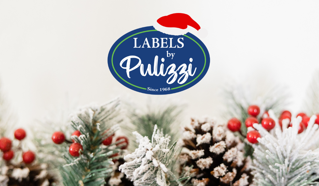Labels By Pulizzi logo with a Santa hat on the logo and a holiday background with frosted pine cones and pine branches and holly berries