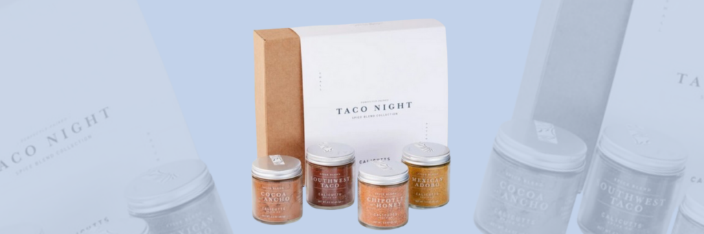 A brown box with the label "Taco Night" on it sitting up with 4 glass containers of seasoning in them in front of the box