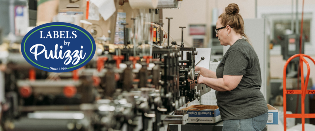 Labels by Pulizzi team member operating precision printing equipment in a professional label manufacturing facility serving regulated packaging markets.